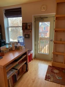 Interior office entry with wooden shelves, wall clock, glass door, hardwood floors, and decorative rug.