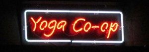 Yoga Co-op neon sign with red and white glowing letters on dark background